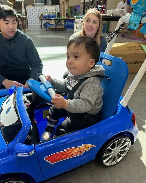 A child using 3D printed parts to operate a GoBabyGo car
